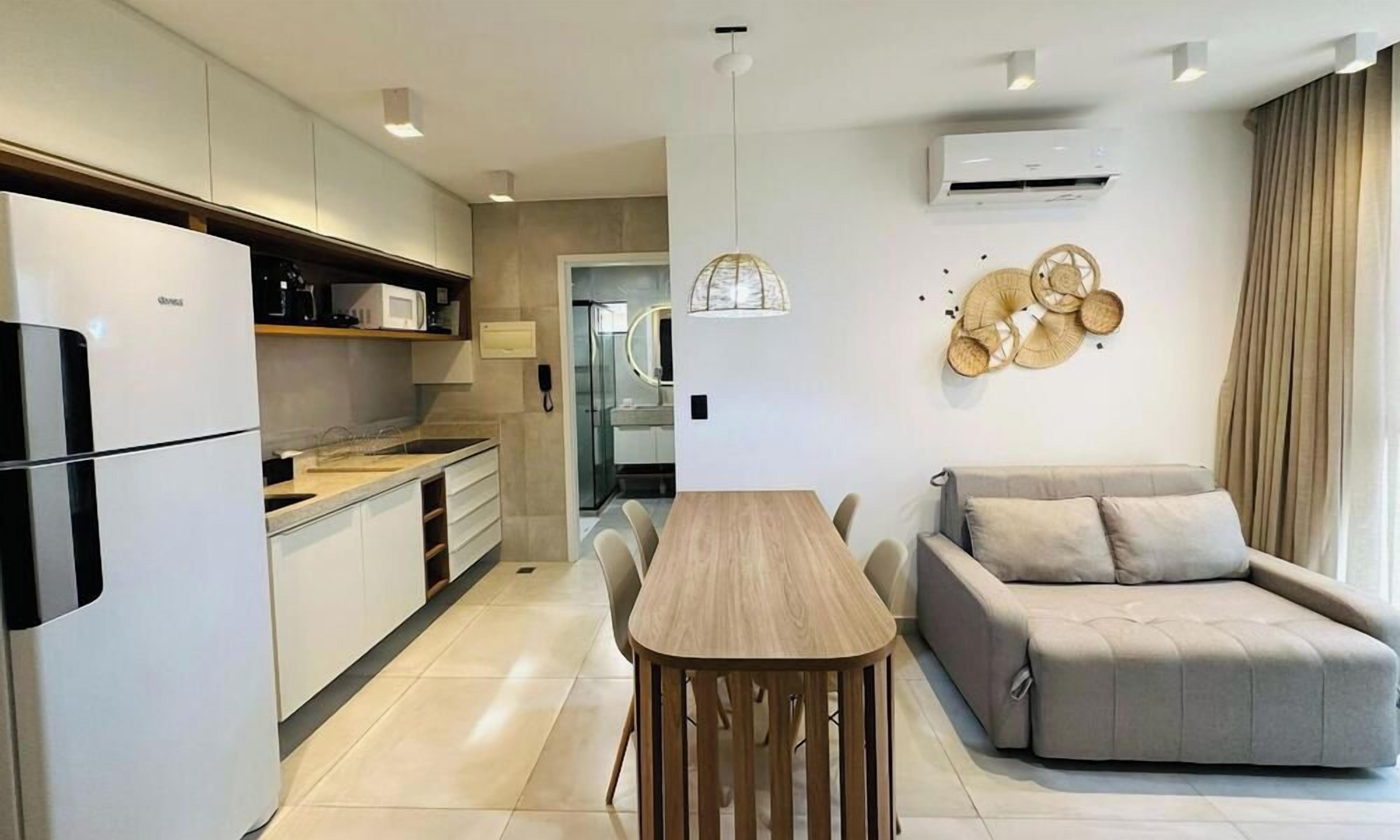 A modern kitchen with built-in appliances, a dining area with a wooden table, and a sofa.