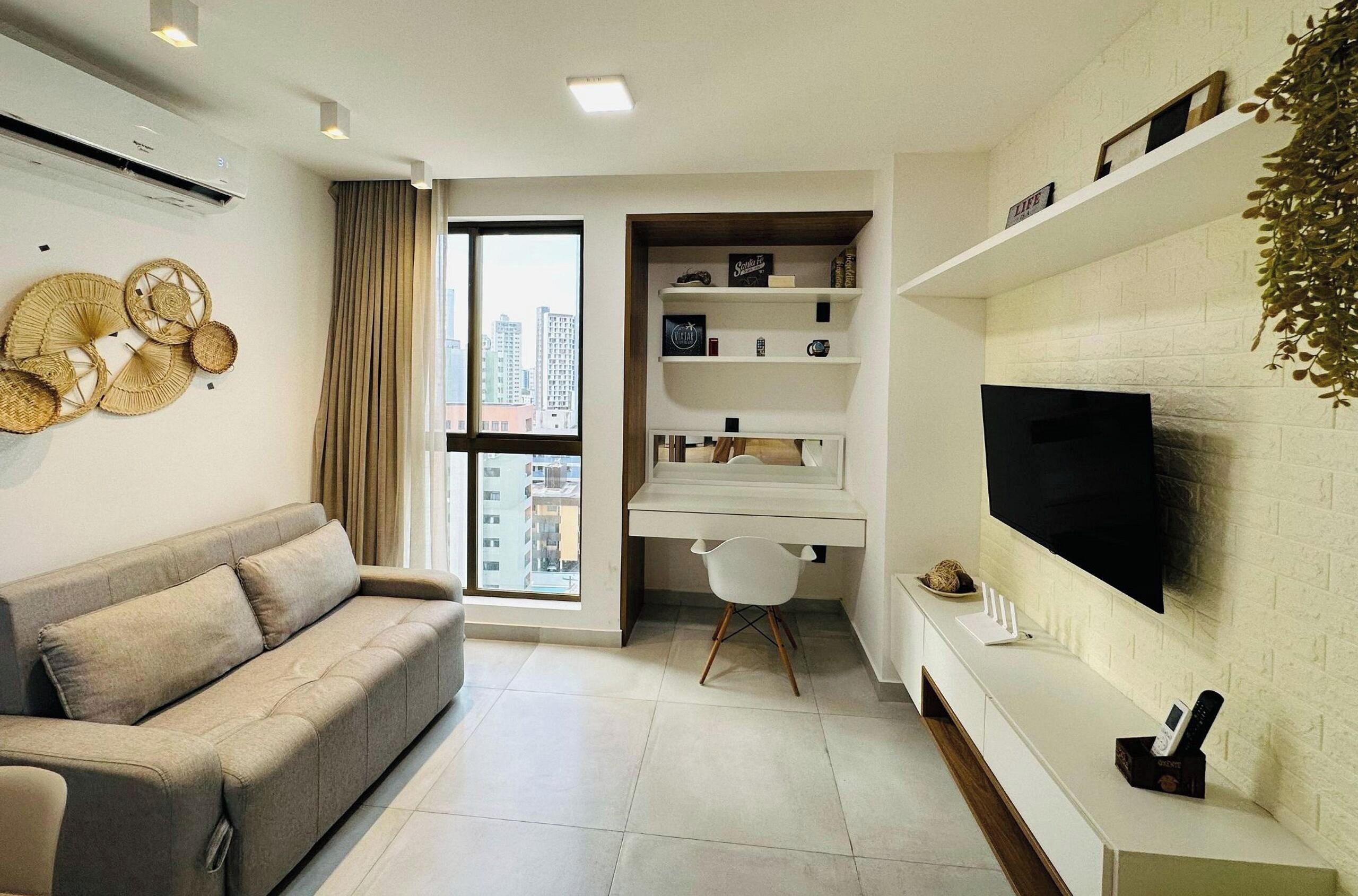 Una sala de estar moderna con un sofá, un escritorio con una silla, un televisor y una estantería.