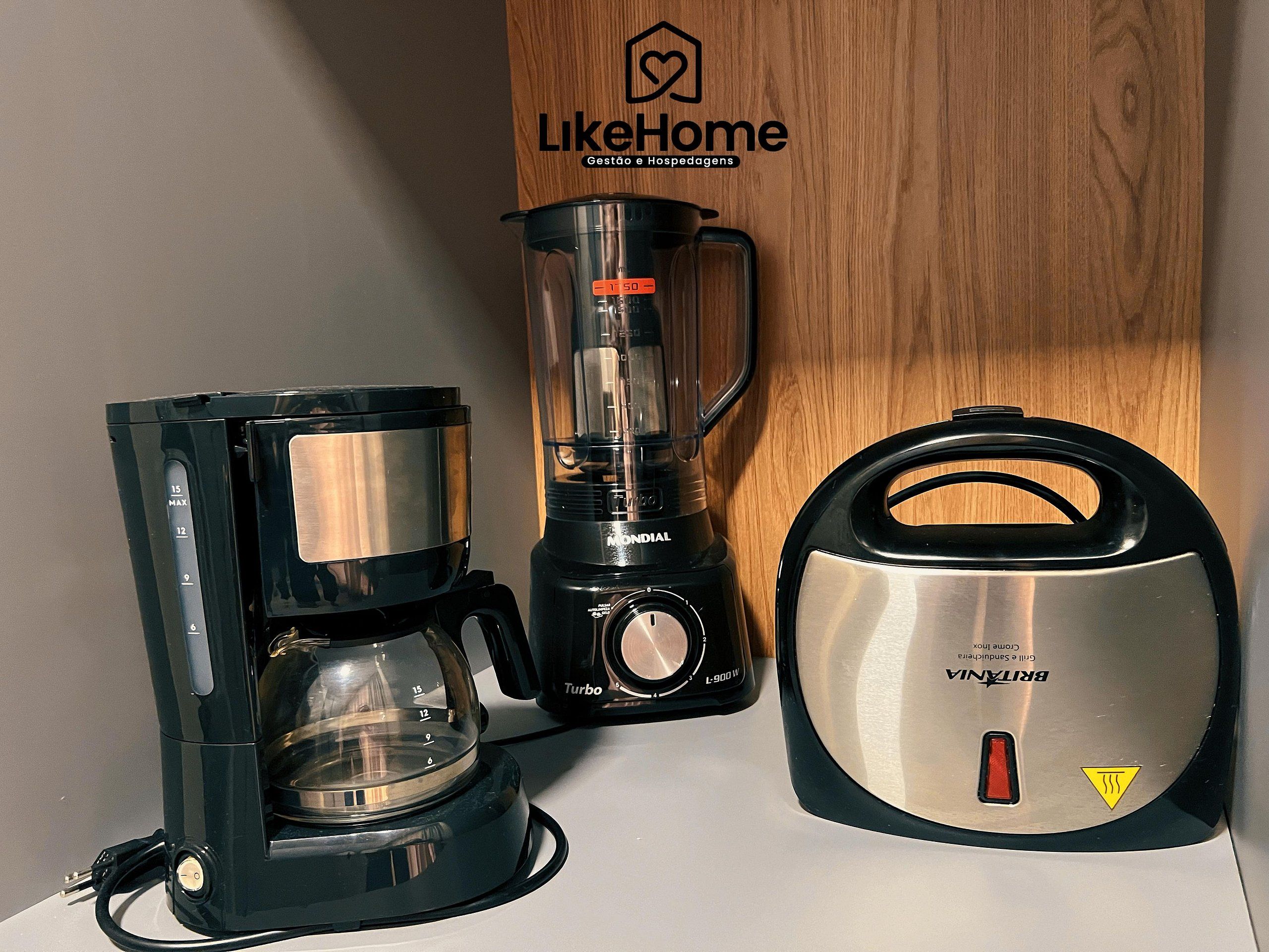 Una cafetera, una licuadora y una tetera sobre la encimera.