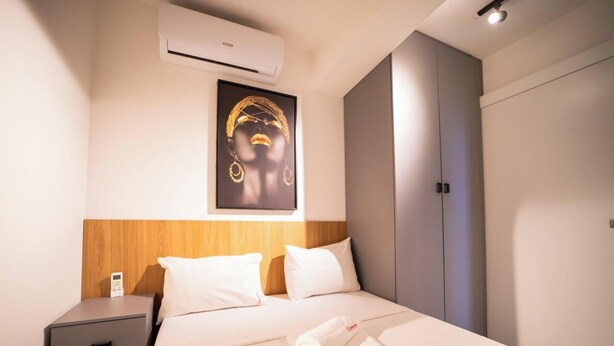 A hotel room with a bed, a nightstand, an air conditioning unit, a wardrobe, and a wall-mounted artwork. - Co-House (João Pessoa)