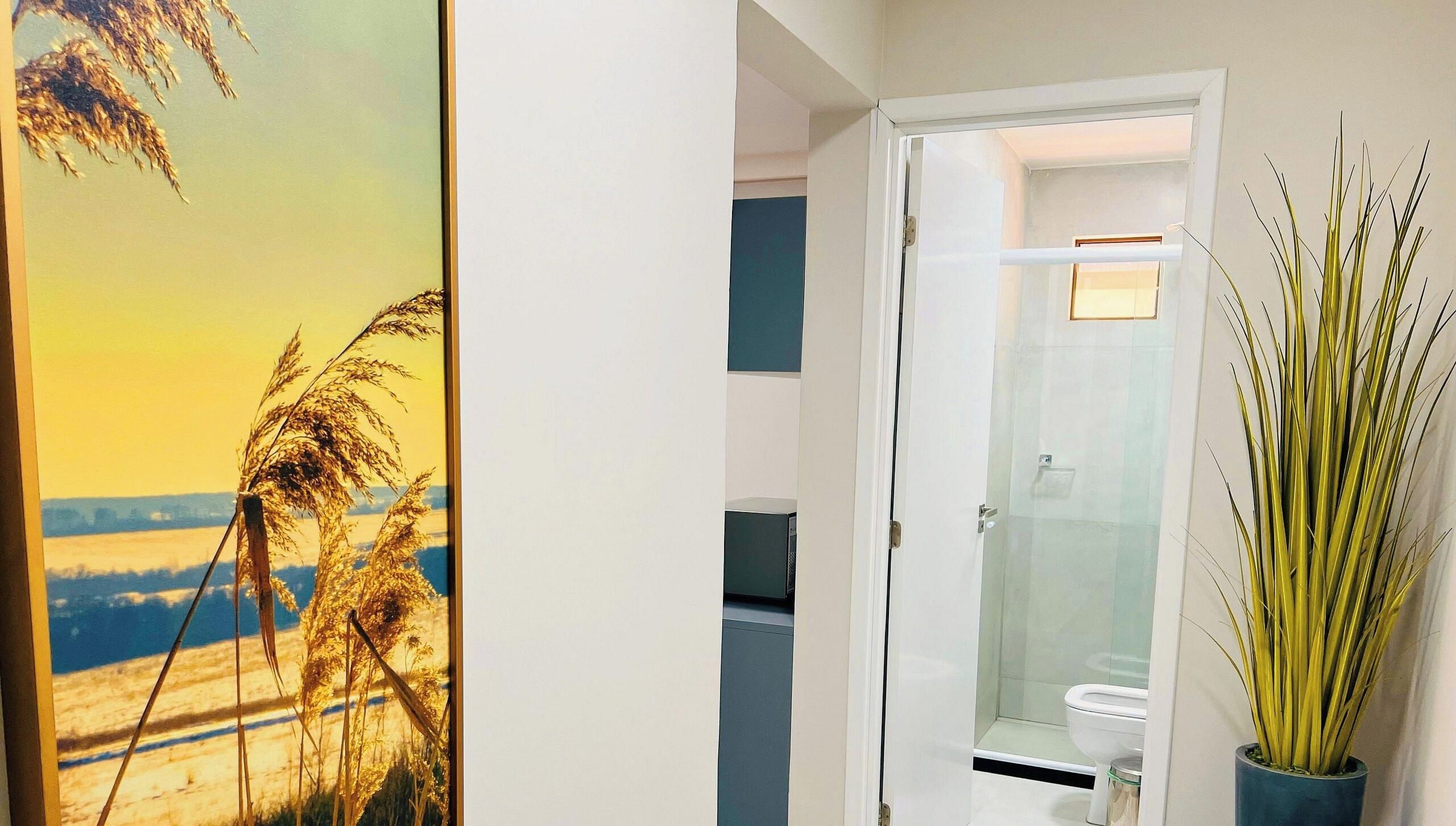 A bathroom with a glass shower enclosure, a toilet, and a potted plant.
