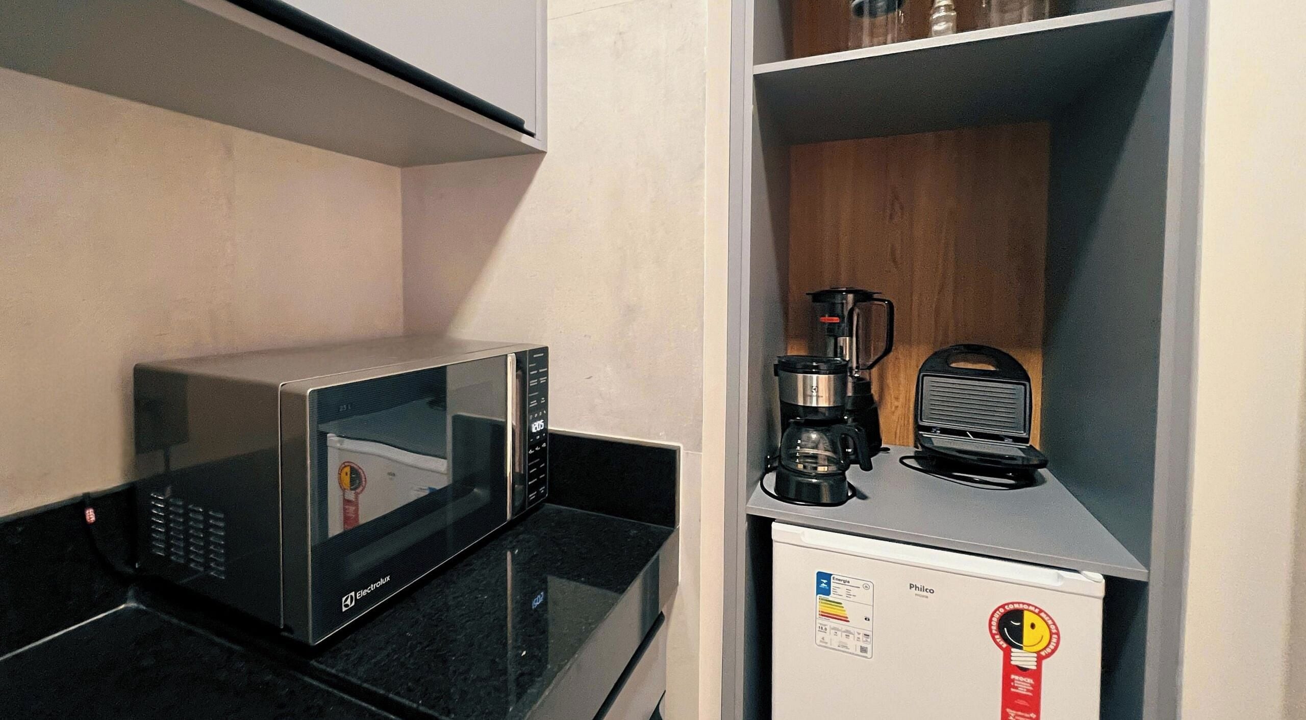 Een kitchenette met een magnetron, koffiezetapparaat en een minibar.