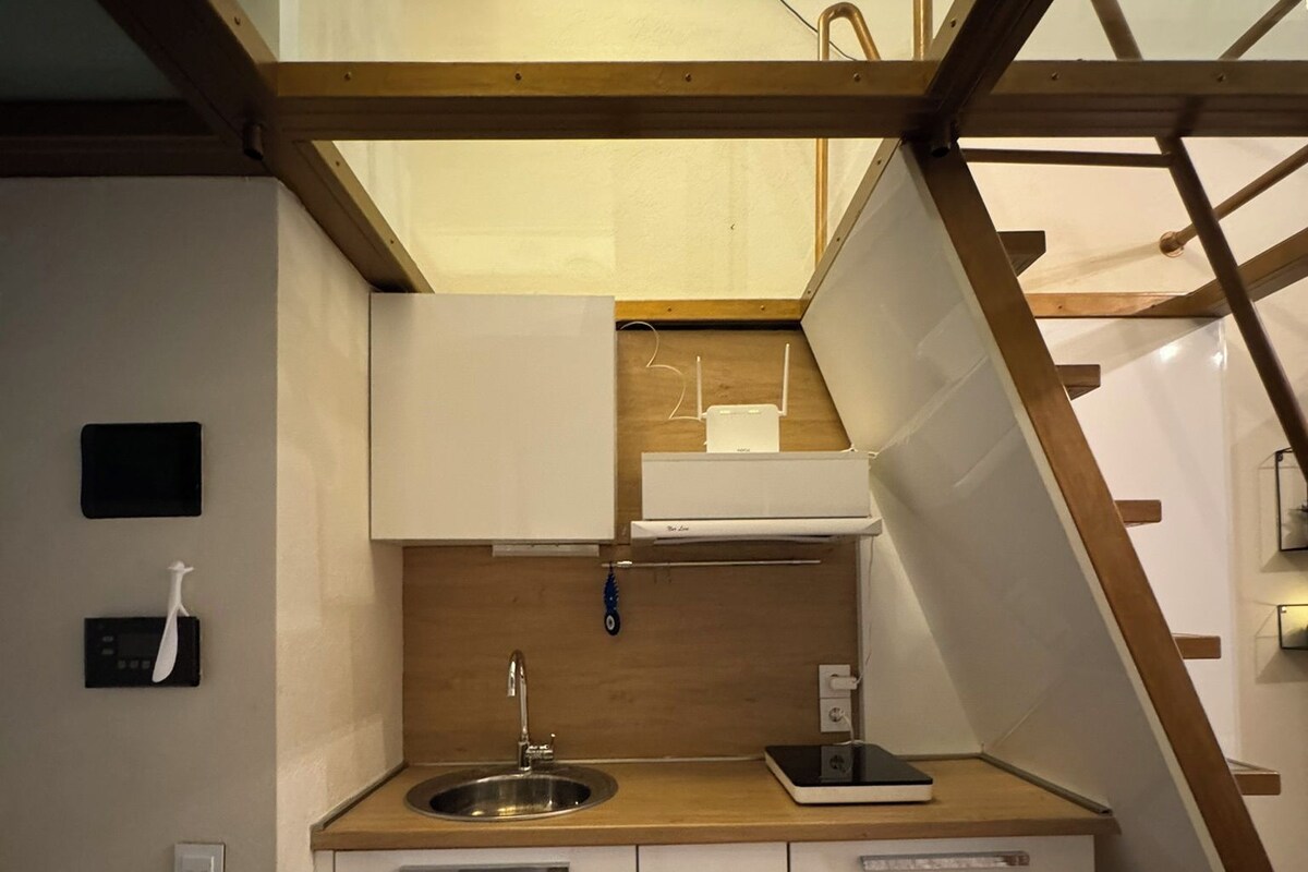 A compact kitchen with a wooden countertop, a stainless steel sink, and white cabinetry.