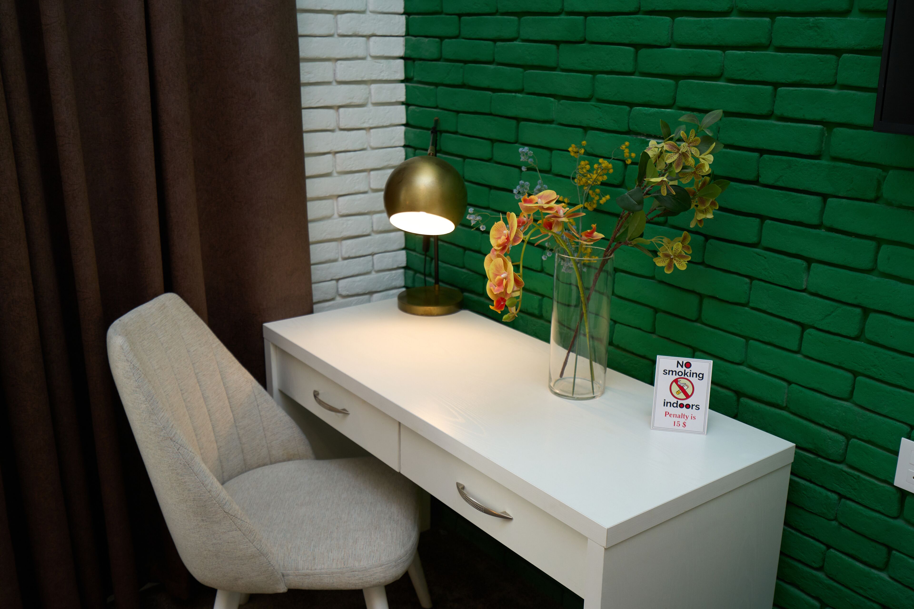 A white desk with a brass lamp, a vase with flowers, and a 'No smoking indoors' sign.