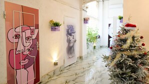Un pasillo con piso de mármol, un árbol de Navidad y obras de arte en las paredes.