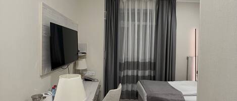 Habitación de hotel con escritorio, silla, cama y televisor.