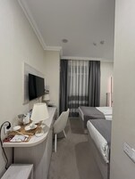 Een hotelkamer met een bureau, stoel, bed en een televisie.