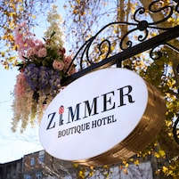 Een bordje voor Zimmer Boutique Hotel, met een bloemstuk erboven.