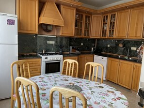 A kitchen with wooden cabinets, a stove, a dishwasher, and a table with chairs.