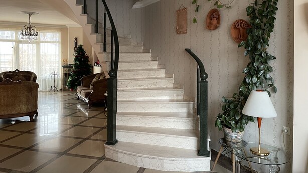 Uma sala de estar espaçosa com uma escadaria de mármore, um candelabro e um pinheiro de Natal.