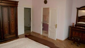 Quarto com uma cama grande, um guarda-roupa e porta para um banheiro.