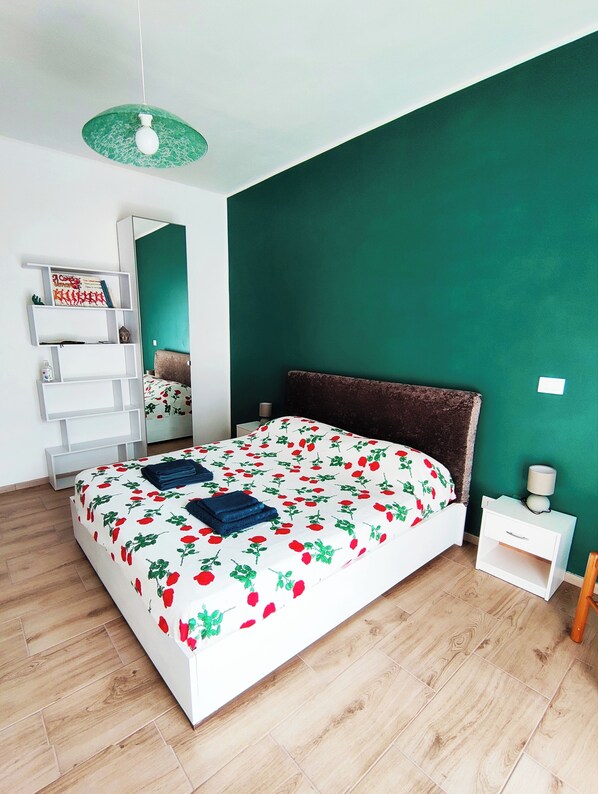 Une chambre à coucher comprenant un lit, une table de chevet, une étagère et un luminaire suspendu.