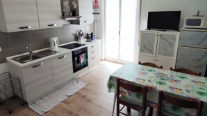 A modern kitchen with a dining area, featuring a microwave, stove, sink, and cabinets. - Renesmee Beach Apartment a 150 Metri Dalla Spiaggia, con Posto Auto Gratuito (Pietra Ligure)
