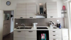 A modern kitchen with light wood cabinets, a stainless steel sink, and a built-in oven. - Renesmee Beach Apartment a 150 Metri Dalla Spiaggia, con Posto Auto Gratuito (Pietra Ligure)