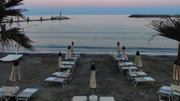 A beach with rows of sun loungers and umbrellas, a calm sea, and a clear sky. - Renesmee Beach Apartment a 150 Metri Dalla Spiaggia, con Posto Auto Gratuito (Pietra Ligure)