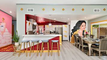 A modern kitchen with a central island, bar stools, and a dining area with a table set for four.