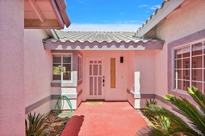 A pink house with a tiled roof, a red pathway, and a door with a window. - Rock N Royalty: Pool, Spa, Fire Pit, Pool Table! (Bermuda Dunes)