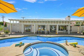 A residential property with a swimming pool, patio area, and a covered outdoor seating space.