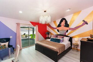 A bedroom with a bed, a chandelier, a large mural, and a view through a glass door. - Rock N Royalty: Pool, Spa, Fire Pit, Pool Table! (Bermuda Dunes)