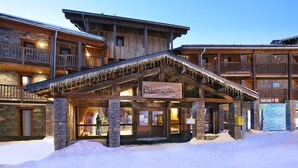 A wooden lodge with a stone facade, a sign reading "Chalet des Nats Arolles," and a ski lift sign. - Wifi, 150m from ski slopes, fitness, swimming pool, sauna, hammam, balcony, fireplace or stove, tv (Les Arcs)