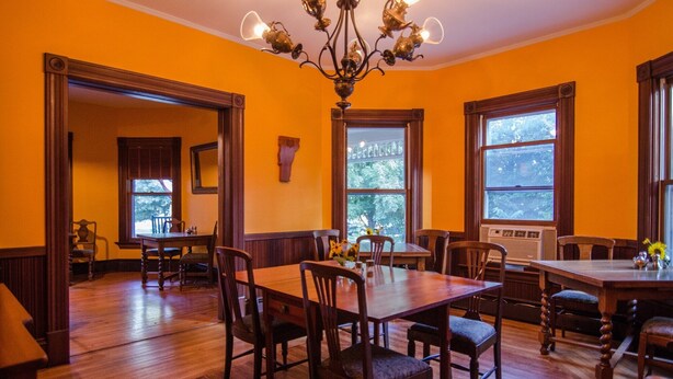Comedor con muebles de madera, ventanas amplias y una araña.