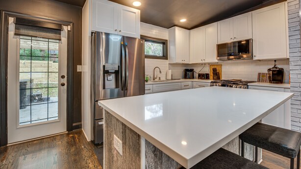 A modern kitchen with white cabinets, stainless steel appliances, and a large island. - Modern Atlanta Retreat: Private Hot Tub & Yard! (Atlanta)