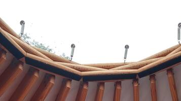 A tent with a wooden frame and a bed with white and brown pillows.