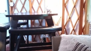 A cozy living room with a wooden floor, a sofa with a fluffy pillow, and a table with a small statue. - Madison's Only YURT Experience  (Madison)