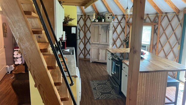 A kitchen with wooden cabinets, a stove, and a wooden staircase. - Madison's Only YURT Experience  (Madison)