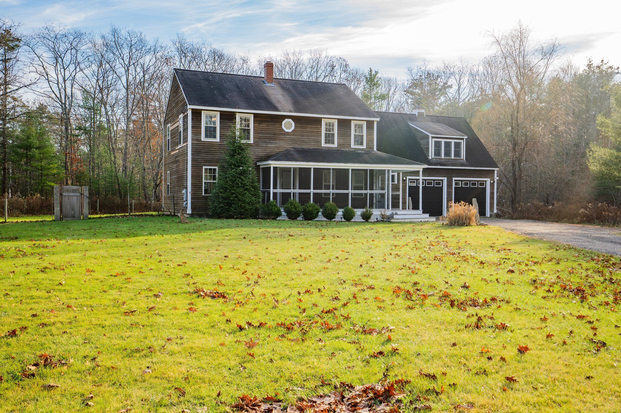 A two-story house with a large front lawn, a garage, and a covered porch.