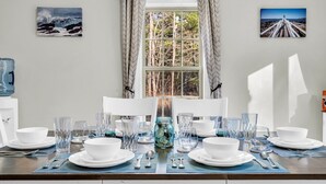 A dining table set with white plates, bowls, and clear glasses, with a jar of decorative items in the center. - Spacious Home Close to Beaches! 3BR, Dog & Family Friendly, 30 Mins to Portland (Biddeford)