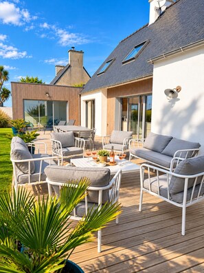 Un patio exterior moderno con un comedor, zona de estar y vista de la casa.