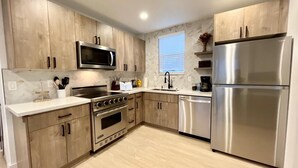 Une cuisine moderne avec des meubles en bois, des appareils en acier inoxydable et un pare-feu en marbre.