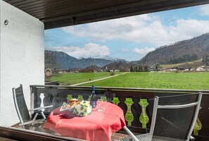 Enjoy a romantic meal for two on this balcony overlooking a serene landscape with a beautiful view of a green field and distant mountains.