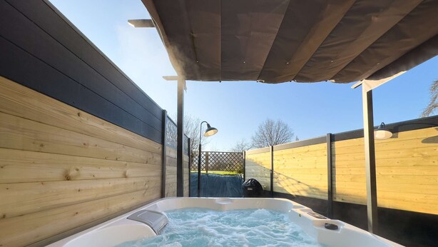 A hot tub with a wooden deck and a covered area.