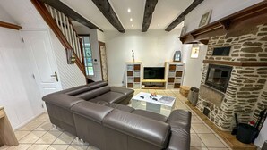 Ein Wohnzimmer mit Ecksofa, Kamin und Fernseher.
