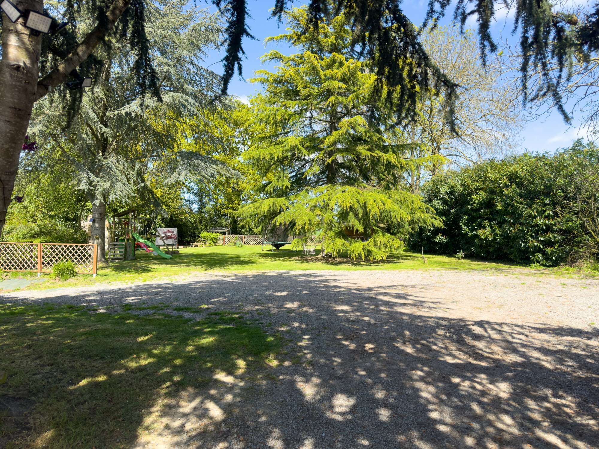 En välskött park med en grusgång, en lekplats och olika sorters träd.