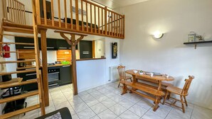 Eine Loft-Wohnung mit Essbereich, Küche und Schlafzimmer im Obergeschoss, verbunden durch eine Holztreppe.