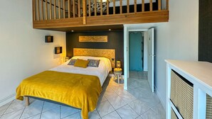 Ein Schlafzimmer mit Hochbett, Nachttisch mit Lampe und kleinem Hocker.