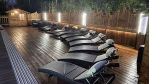 Eine Terrasse mit Liegestühlen und einer Holzhütte.