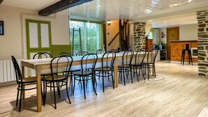 Un comedor con una mesa larga y sillas, una pared de piedra y una viga de techo de madera.