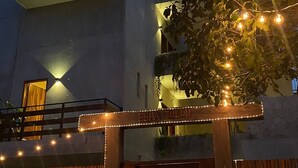 A modern building with a flat roof, a balcony, and a wooden gate with lights. - Esha Tulum (Tulum)