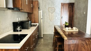 A modern kitchen with wooden cabinets, a black stove, and a marble countertop. - Esha Tulum (Tulum)