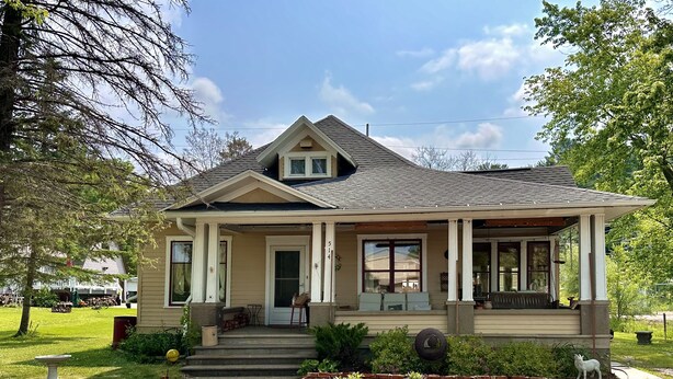 A single-story house with a gabled roof, a front porch, and a small front yard with mulch and plants. - Colorful getaway in friendly Driftless village (Wonewoc)