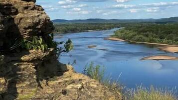 Een rotsachtige klif met uitzicht op een rivier, onder een heldere lucht.