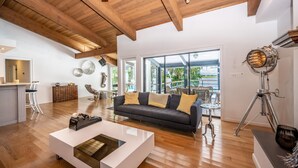 Un salón amplio con un sofá gris oscuro, suelo de madera y una mesa de centro blanca.