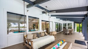 Un amplio espacio exterior con una mecedora, una mesa de comedor y vistas a una piscina.