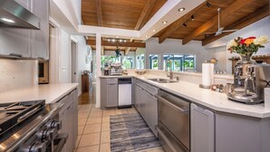 Una cocina moderna con una isla central, electrodomésticos de acero inoxidable y techo de madera.