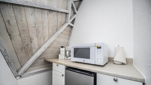 Una kitchenette compacta equipada con microondas, cafetera y lavavajillas.