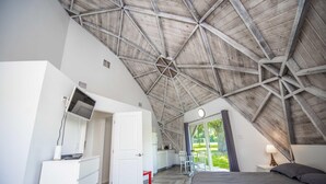 A bedroom with a sloped ceiling, a bed, a desk with a chair, and a view of the outdoors. - Studio 01 - Lake Sumner (Clermont)